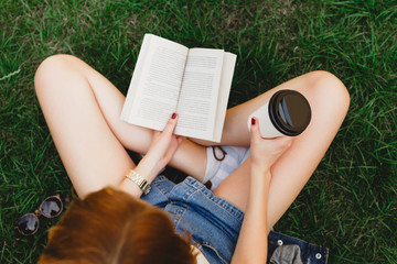 The girl sitting on a grass with cup of coffee