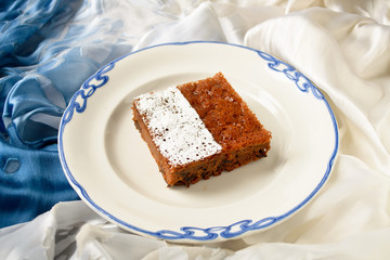 Piece of chocolate cake with frosting on blue background