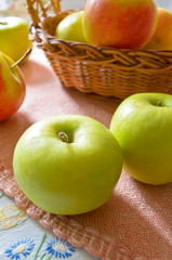 Green and red organic apples in basket