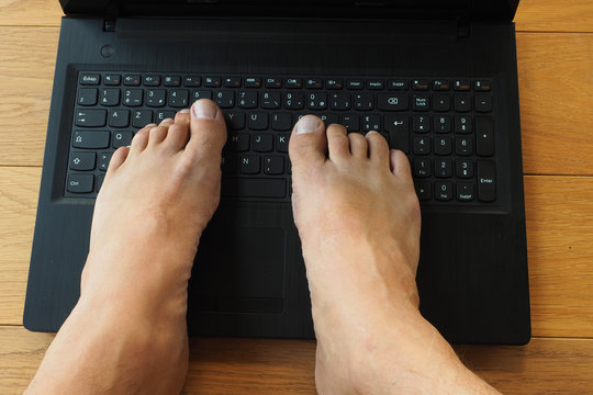 Personne incomp&eacute;tente en informatique avec les 2 pieds sur un clavier d'ordinateur