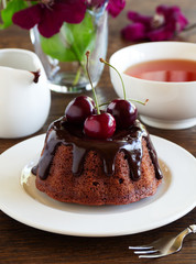 Chocolate cake with icing and a cherry.