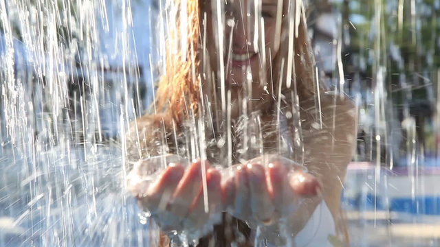 Crystal clear streams of water fall on the young woman's hands.