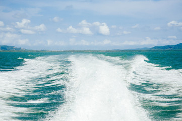 Wave from speed boat on the sea and blue sky white cloud
