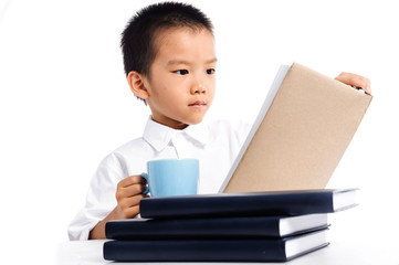 Young boy has a cup of milk reading book