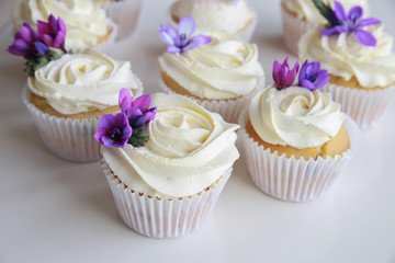 Edible purple freesia flowers on vanilla cupcakes with whipped c