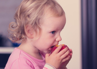 Funny little girl (2 years) eat a peach.