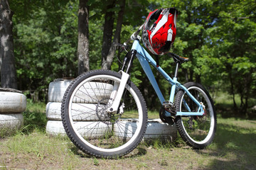 Mountain biking with helmet on steering wheel  is a clearing in the forest near the trees and white tires