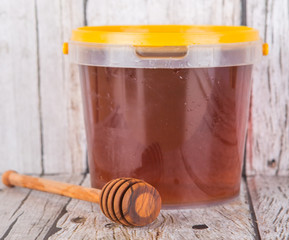 Wooden honey dipper with natural honey over wooden background