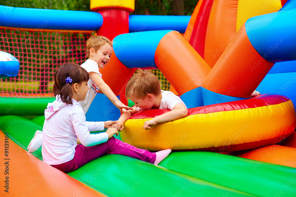 Wall mural excited kids having fun on inflatable attraction playground