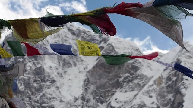 Prayer flags fluttering in the wind with snowy Himalayan mountains in the background, Everest Region, Nepal.