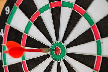 Red dart sticking in the target, hit the target on a wooden back