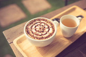 A Latte Coffee art on the wooden desk with tea cup vintage color