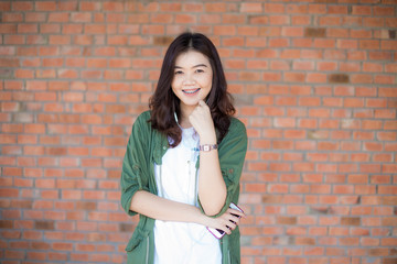 Happy asian woman with black Hair standing Against Old Brick Wal