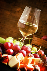 White wine, cheese, figs, nuts and grapes on the old wooden back