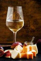 White wine, cheese, figs, nuts and grapes on the old wooden back