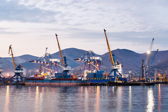 Port cranes in dock by sea at twilight