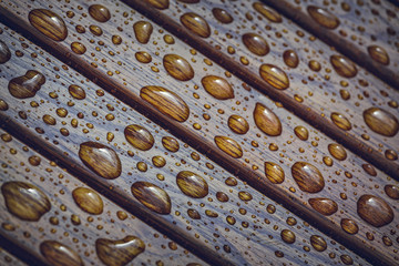 Water drops, raindrops pattern on wooden bench planks. Shallow depth of field.