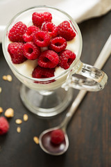 Healthy breakfast with muesli, yogurt and raspberries on dark wooden background
