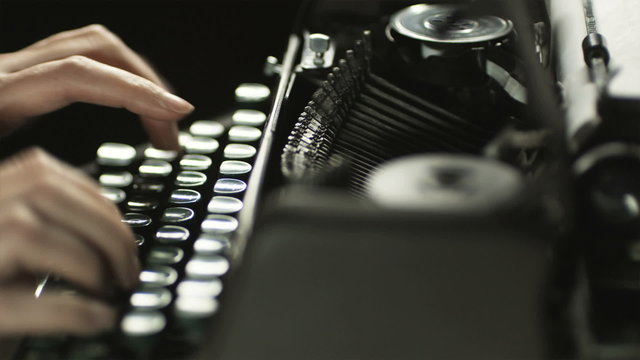 fingers typing on the keyboard of an old-fashioned typewriter