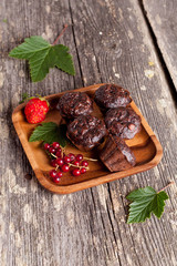 Chocolate muffin with red currant on wooden background