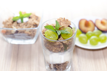Glass and bowl fill up with muesli, yogurt, mint