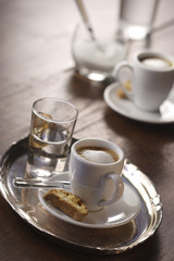 A cup of espresso macchiato with cantuccini and a glass of water