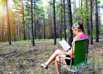 Beautiful girl reading a book on the nature