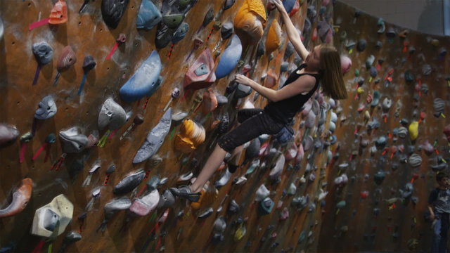teenage girl free climbing an indoor climbing wall