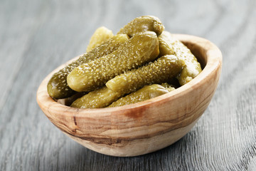 marinated cornichons in wooden bowl