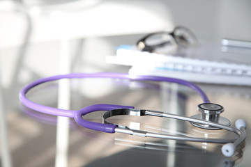 Purple stethoscope on the glass desk