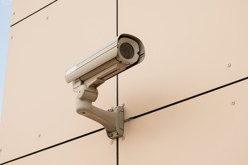 White security camera devices on light gray building.