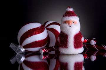 Christmas decorations fluffy santa 2 candy canes and 2 balls red and white shot front on on a grey...