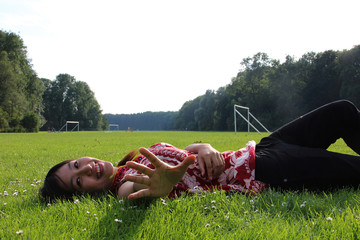 A young Asain woman lying on a grass field