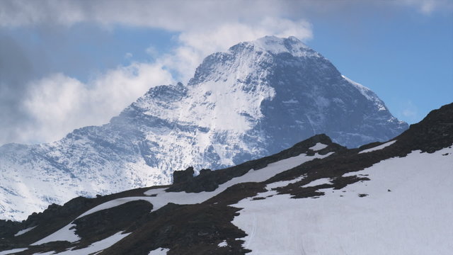 clouds passing over a snowcapped mountain range