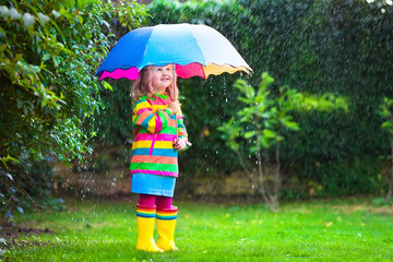 Little girl with colorful umbrella playing in the rain.