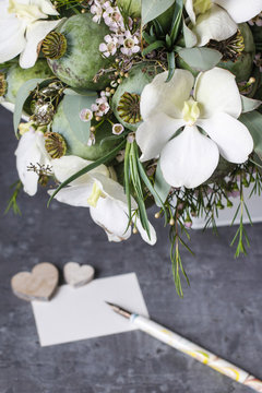 Modern bouquet with white orchid flowers and green poppy heads.