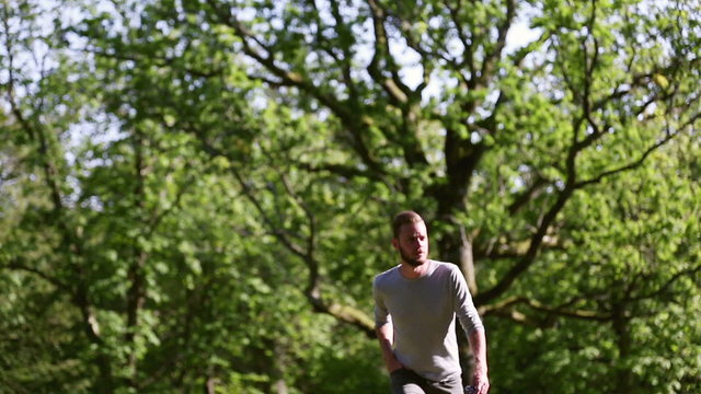 A lonely man wearing a grey shirt, walking in a park on a sunny summer day. Wearing a grey shirt and jeans.