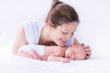 Young mother and newborn baby in white bedroom