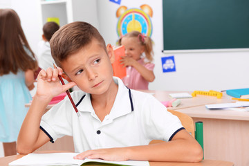 Fototapeta premium Little boy drawing at the desk in classroom