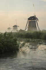 Foggy windmills on a dike
