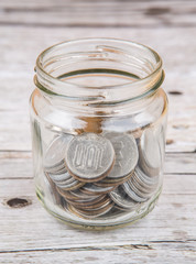 Japanese Yen coins in a mason jar over wooden background