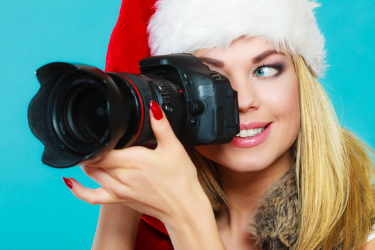 Photographer girl in santa claus hat shooting images