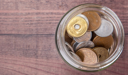 Japanese Yen coins in a mason jar over wooden background