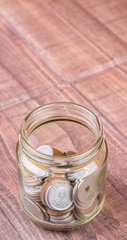 Japanese Yen coins in a mason jar over wooden background