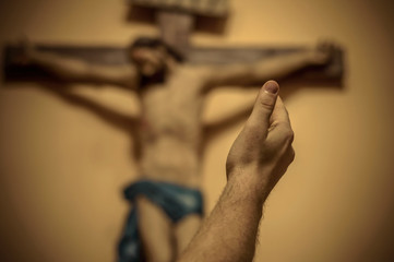 Artitic vignette edit of a man's hand raised towards Jesus on th