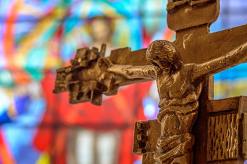 Bronze crucifix of Jesus Christ in a church with stained glass b
