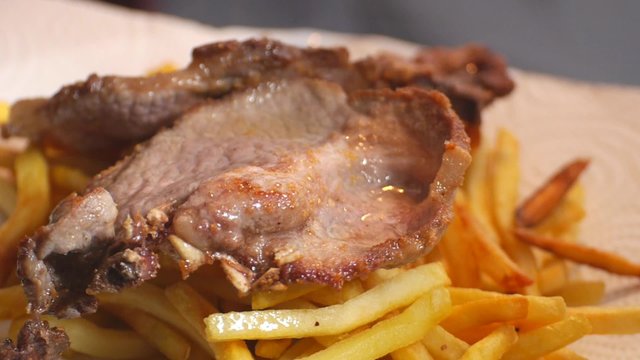 servir chuleta de cerdo grasa sobre patatas fritas