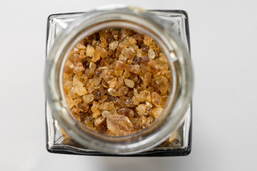 Brown rock candy crystals sugar in glass bottle on white background