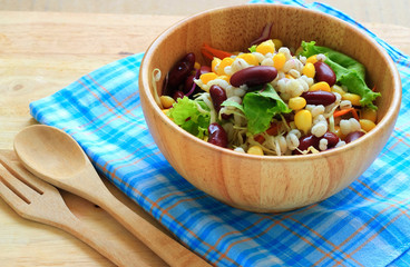 Healthy salad with fresh vegetables on wood background