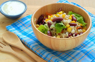 Healthy salad with fresh vegetables on wood background